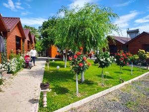 a woman walking through a garden with trees and flowers at Cabanele Deltei in Dunavăţu de Jos