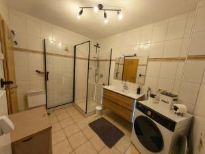 a bathroom with a shower and a sink and a washing machine at Ferienwohnung Look wide in Oberelsbach +18 photos