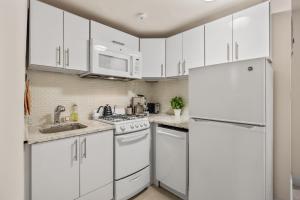 a kitchen with white cabinets and a white refrigerator at Chic One Bedroom Retreat in Downtown Manhattan in New York
