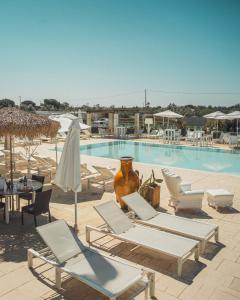 una piscina con sedie a sdraio e un tavolo e una piscina di Borgo Rosso Terra a Gallipoli