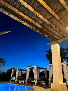 un gruppo di sedie sotto un pergolato a bordo piscina di Borgo Rosso Terra a Gallipoli