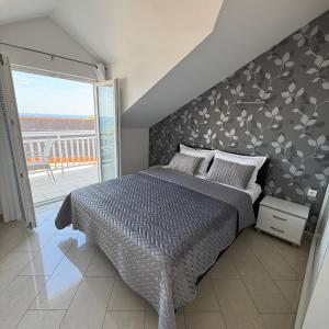 a bedroom with a large bed with a floral accent wall at Apartments Kutlic in Cavtat