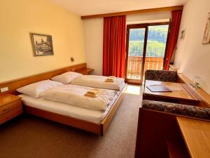 a bedroom with two beds and a desk and a window at Pension Thalerhof in Rifiano