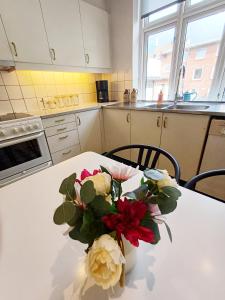 a white table with a vase of flowers on it at Exclusive Luxury Apartment with free private parki in Aalborg
