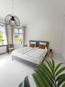 a white bedroom with a large bed and a plant at Exclusive Luxury Apartment with free private parki in Aalborg