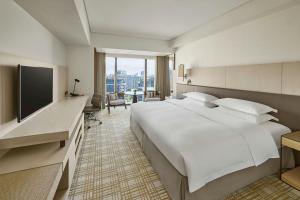 a hotel room with a large bed and a flat screen tv at Taipei Marriott Hotel in Taipei