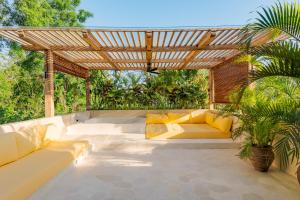 an outdoor patio with couches and a wooden pergola at La Isla Boutique Residences in Uluwatu