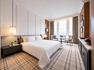 ein Schlafzimmer mit einem großen weißen Bett und ein Wohnzimmer in der Unterkunft Marqen Hotel in Jakarta
