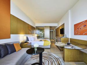a hotel room with a bed and a living room at Mövenpick Siam Hotel Na Jomtien Pattaya in Na Jomtien