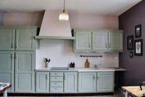 a kitchen with green cabinets and a sink at Maison de charme in Bourgueil