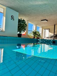 a swimming pool with blue tile floors and windows at Pension Thalerhof in Rifiano