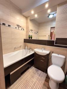 a bathroom with a toilet and a tub and a sink at Mieszkanie w Centrum Hajnówki-Brama Puszczy Białowieskiej in Hajnówka
