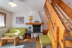 ein Wohnzimmer mit einer grünen Couch und einer Treppe in der Unterkunft Ciasa pe de Bosc in Mazzin