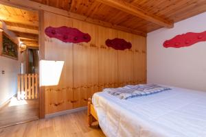 ein Schlafzimmer mit einem Bett mit roten Bettdecken an der Wand in der Unterkunft Ciasa pe de Bosc in Mazzin