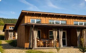 a wooden house with a table and chairs in front of it at Prozori Boiky in Lopushanka-Khomyna