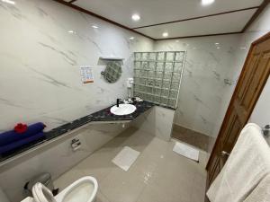 a white bathroom with a sink and a toilet at Beach Villa Guesthouse in Grand Anse