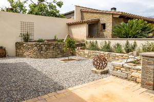 a backyard with a stone retaining wall and a house at Casa Romaní– Alojamiento acogedor in Miánegas