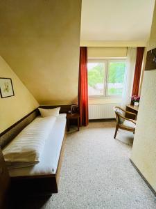 a bedroom with a bed and a window and a chair at Hotel Bürkls Kirnbachtal in Niefern-Öschelbronn