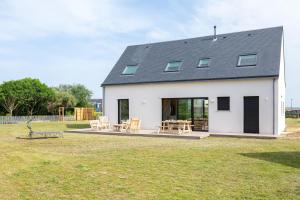 a white house with a black roof at Aux flots de la Torche, 3ch in Penmarch