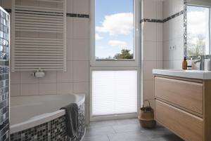 a bathroom with a tub and a sink and a window at Design-FeWo Fleesensee, Wallbox, Sauna, Terrasse in Unter Göhren +20 photos