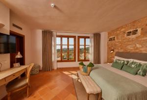 a bedroom with a bed and a desk and a window at Hotel Rural Es Riquers in Porreres