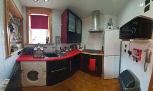 a kitchen with a red counter top and a refrigerator at FREE DOG STAY - LARGE APARTMENT - FREE PUBLIC PARKING BEDROOM TV, WALK in SHOWER - FULL Kitchen - NETFLIX - Super Fast WiFi - DVD's-Welcome Tray - No Deposits - Just Meters from Gavin n Stacey Film House in Barry