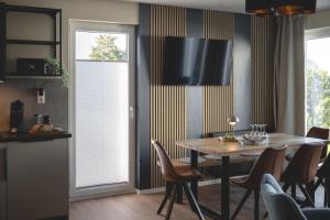 a dining room with a wooden table and chairs at Design-FeWo Fleesensee, Wallbox, Sauna, Terrasse in Unter Göhren