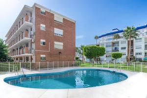 a swimming pool in front of a building at Luxury White Summer Benalmadena in Benalmádena
