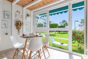 a dining room with white chairs and a table and windows at Luxury White Summer Benalmadena in Benalmádena +19 photos