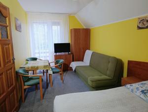 a hotel room with a green couch and a chair at Dom Pod Gruszką in Pobierowo