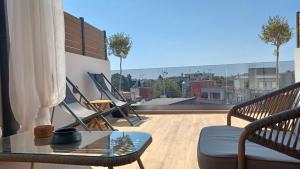 a balcony with a glass table and chairs on a roof at attico di lusso in Komotini