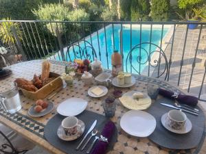 a table with breakfast food on it next to a pool at Bouzigues Suite Parentale Étang de Thau in Bouzigues