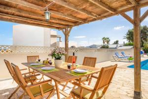 a wooden table and chairs on a patio with a swimming pool at Villa Claudia by Villa Plus in S'Algar