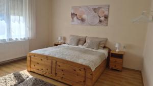 a bedroom with a large wooden bed with two night stands at Akácfa Vendégház in Makó