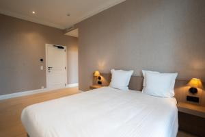 a bedroom with a large white bed with two lamps at Hotel Lodewijk Van Male in Bruges +28 photos