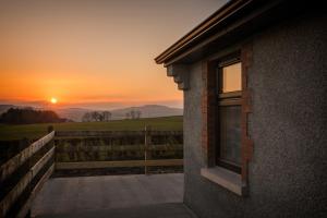 a window of a house with a sunset in the background at Elagh Cottages in Derry Londonderry
