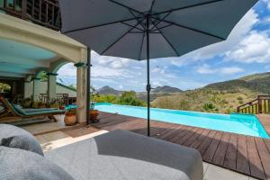 a patio with an umbrella and a swimming pool at Studio Lili in Le Diamant