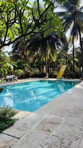 a blue swimming pool with palm trees in the background at Niwas Villa in Vihur
