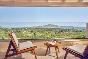 ein Zimmer mit zwei Stühlen, einem Tisch und einem großen Fenster in der Unterkunft Ether Villa View in Lithakia