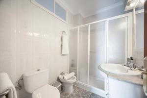 a white bathroom with a toilet and a sink at En la Gloria in Barbate