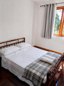 a bedroom with a bed with two pillows and a window at Refúgio na Serra - natureza e conforto in Teresópolis