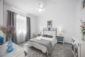 a white bedroom with a bed and a blue vase at En la Gloria in Barbate