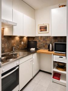 a kitchen with white cabinets and a sink and a microwave at Mountain Holiday Leukerbad Free Parking and WiFi Playroom 96 in Leukerbad
