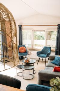 a living room with a couch and chairs and a table at Forrest Lodge in bosrijke omgeving de Veluwe - met terras, tuin en fietsschuurtje in Nunspeet