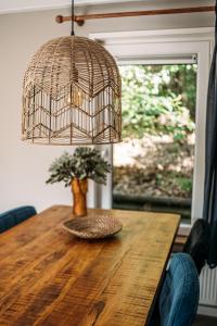 a dining room table with a bird cage lamp and a vase at Forrest Lodge in bosrijke omgeving de Veluwe - met terras, tuin en fietsschuurtje in Nunspeet
