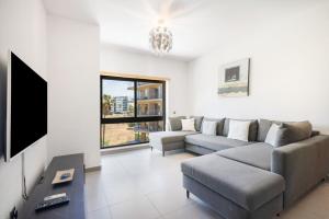 a living room with a couch and a tv at Parque Atlântico Apartment in Quarteira