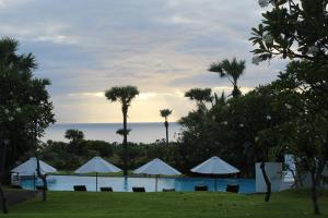 a view of a pool with umbrellas and palm trees at Palm Springs Bali Dive Resort in Tulamben +41 photos