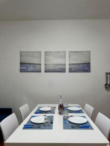 a white dining room table with white plates and chairs at Casa Tropea Vibes in Tropea