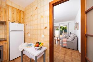 a kitchen and living room with a table and a refrigerator at Villa Ponent in Port d'Addaia