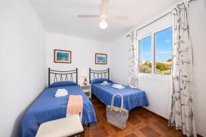 a bedroom with two beds and a window at Villa Ponent in Port d'Addaia +21 photos